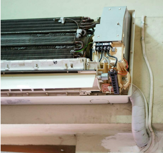 AC repair technician inspecting indoor unit wiring in Multan