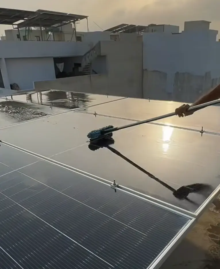 UrbanFix team washing solar panels with a long soft brush on a Multan rooftop